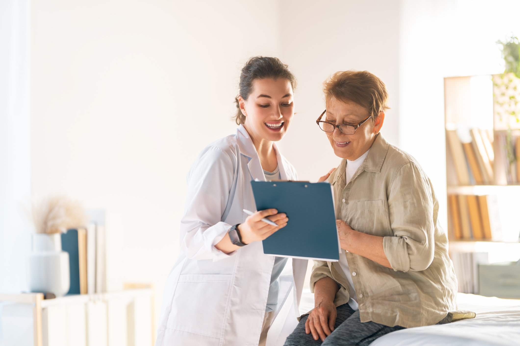 Heartwarming interaction between a cheerful young female doctor and a happy elderly patient, sharing positive medical news in a sunlit healthcare setting. The scene radiates trust, compassion, and professional care, making it ideal for promoting medical services, senior healthcare, patient trust, and supportive doctor-patient relationships.